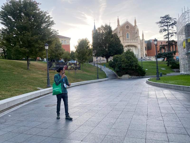 Male tour guide standing in the walkway of the Prado with a church in the background
