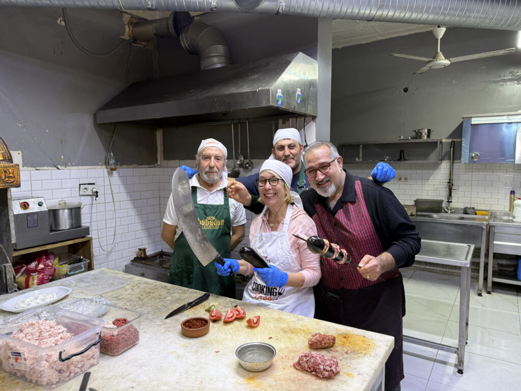 Author posing with several chefs and a large cleaver in the kitchen of Babadan Lezzetler Usta Isleri.