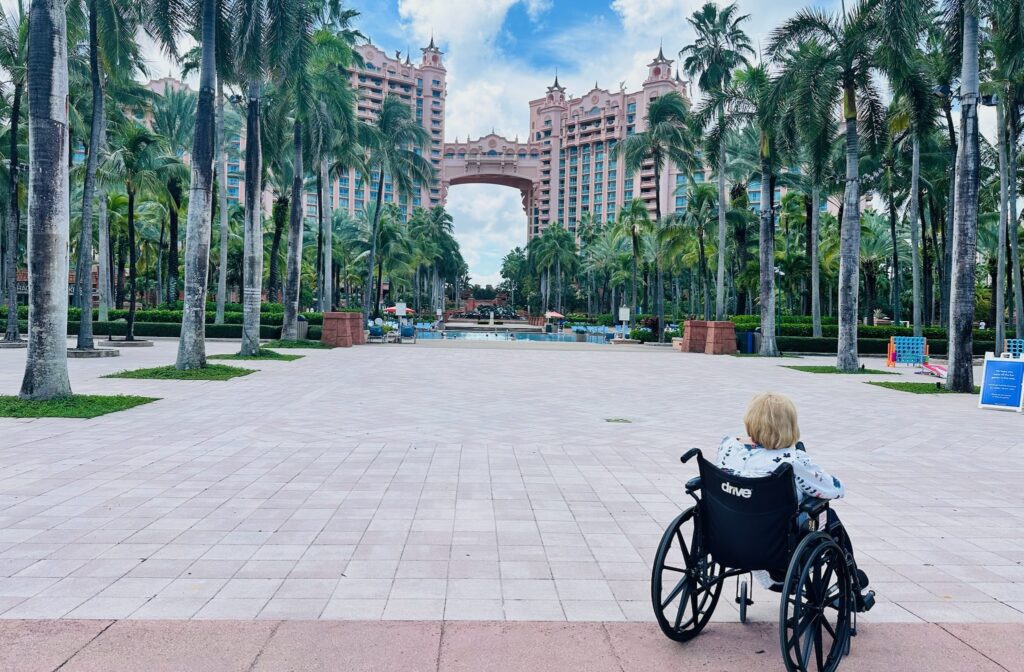 A woman in a wheelchair looks at the iconic towers of the Atlantis Paradise Island Bahamas resort.