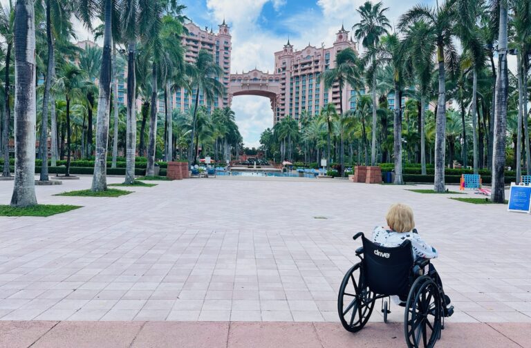 A woman in a wheelchair looks at the iconic towers of the Atlantis Paradise Island Bahamas resort.