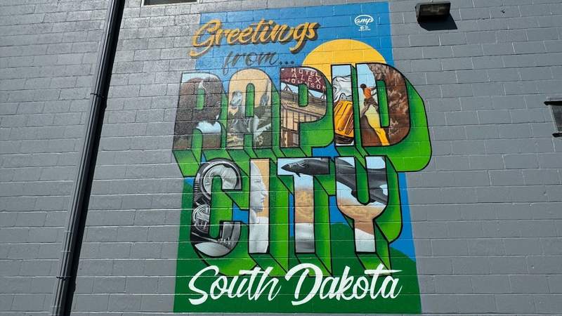 Colorful green, blue and yellow rapid city mural on a gray wall in downtown Rapid City.