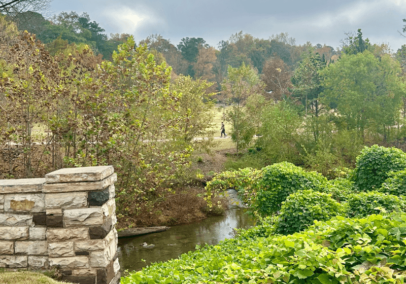 Distant view of figure behind creek and stone wall