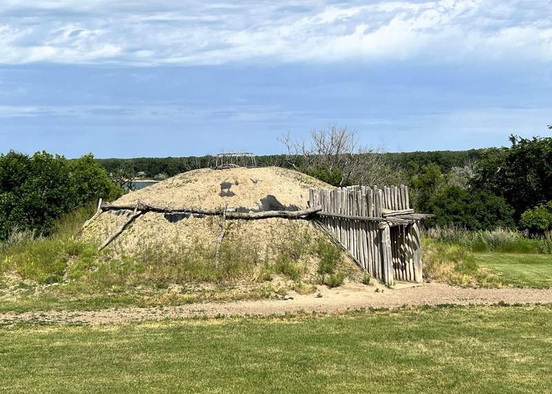 Exterior of a hollowed mound of earth with an entrance door made up vertical beams