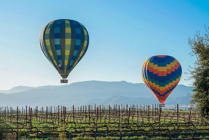 Hot air balloons floating over Temecula vineyards.
