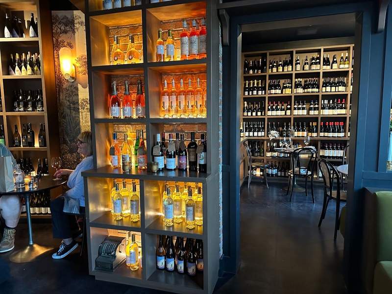 Wine bottles line the wall and shelves while a couple sits at a table at Two Travelers in Temecula.