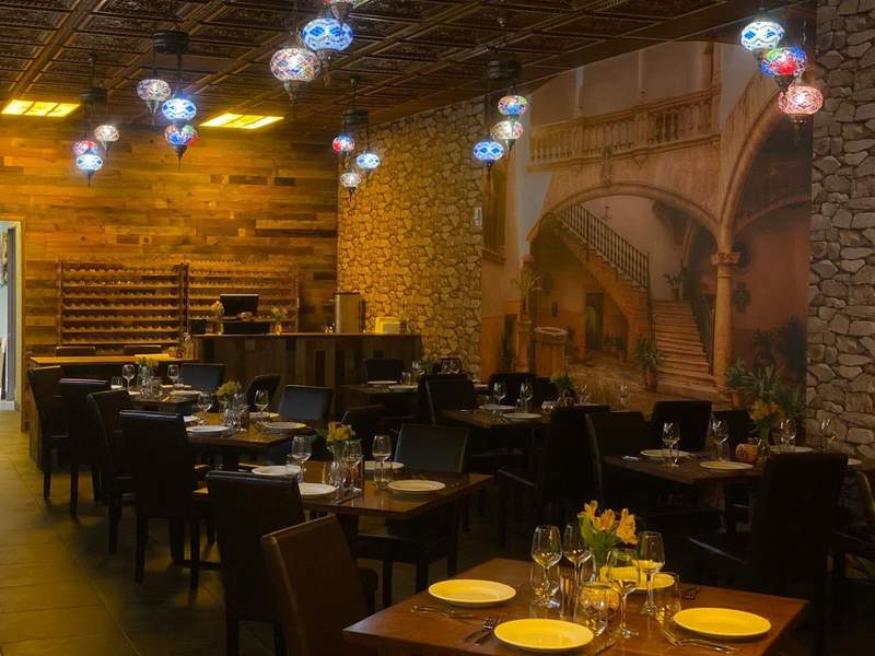 Tables are set with plates wine glasses and flowers in the dimly lit Kan Zaman restaurant in Murrieta.