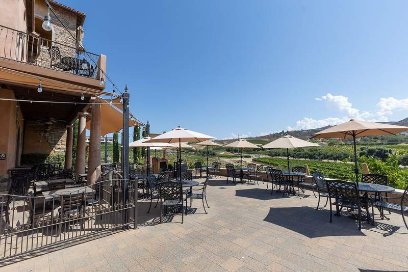 Wrought iron tables with umbrellas overlook vineyards at Mama Rosas Trattoria in Temecula.