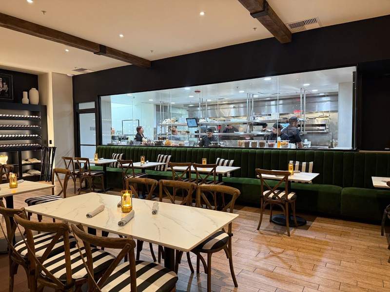 Tables are set in front of a glass window displaying an open kitchen at Domenicos Steakhouse in Temecula.