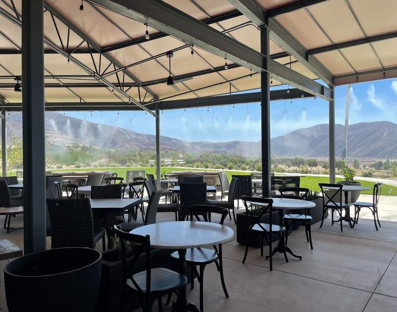Misters cool patio tables overlooking vineyards at Altisima in Temecula.