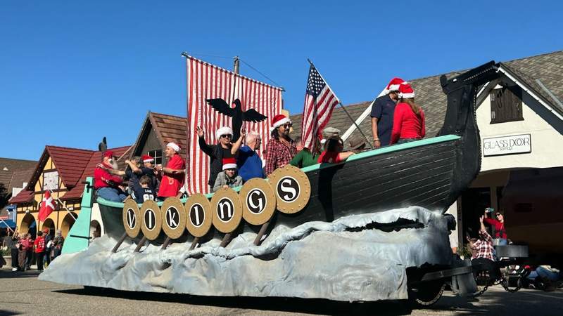 long wooden boat with circular letters spelling viking and people standing inside in Santa hats at Solvang Julefest 