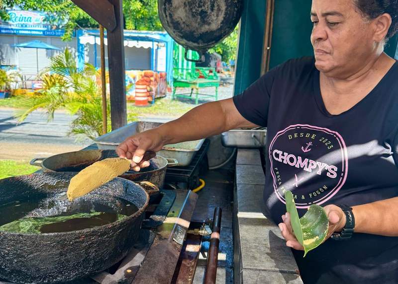 Woman puts an alcapurria in hot oil to cook