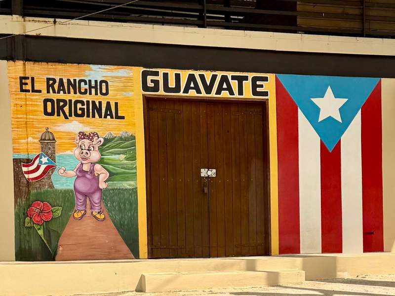 A mural for Guavate promotes El Rancho Original with a pig holding a Puerto Rican flag