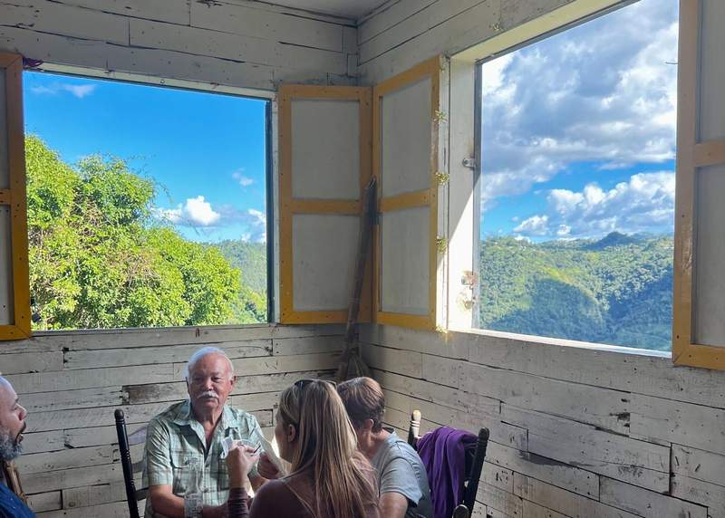 People dine in a restaurant with open windows showcasing mountain views