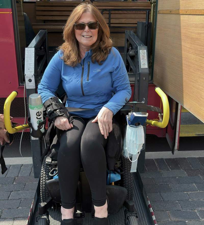 Marcia Frost, in a black pants and blue top, sits in her wheelchair on the Historic Cheyenne Trolley Lift, waiting to go up.