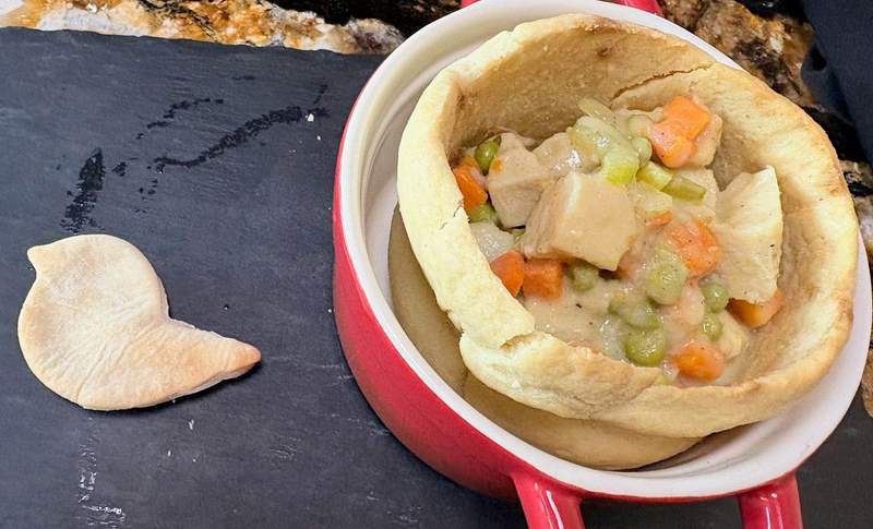 A piece of crust in the shape of a dove next to an open pie crust filled with chicken and vegetables from Paris West in Cheyenne.