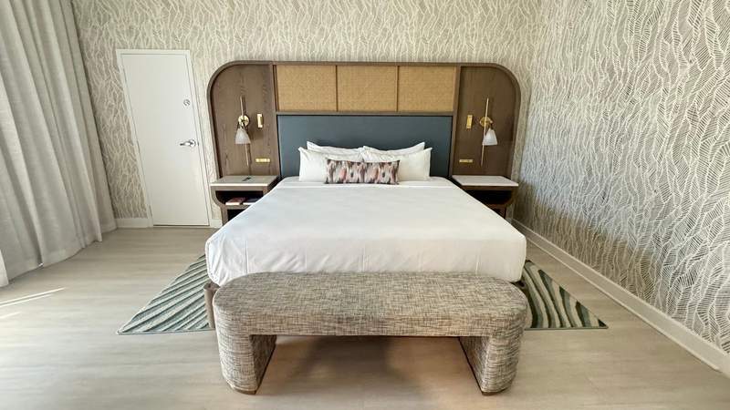 large bed with foot bed and wooden headboard with striped rug and leaf wall paper at sonesta resort hilton head island