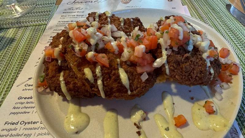 three fried green tomatoes on a plate with red diced bruschetta and a sauce drizzle from Sonesta Resort Hilton Head Island