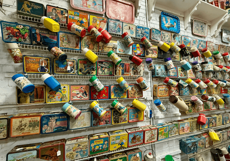 Vintage lunchboxes hanging along a wall inside a museum.