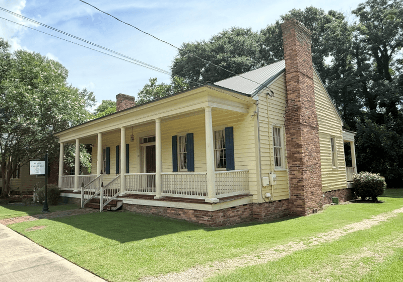 Small cottage with neat front yard and a brick chimney.
