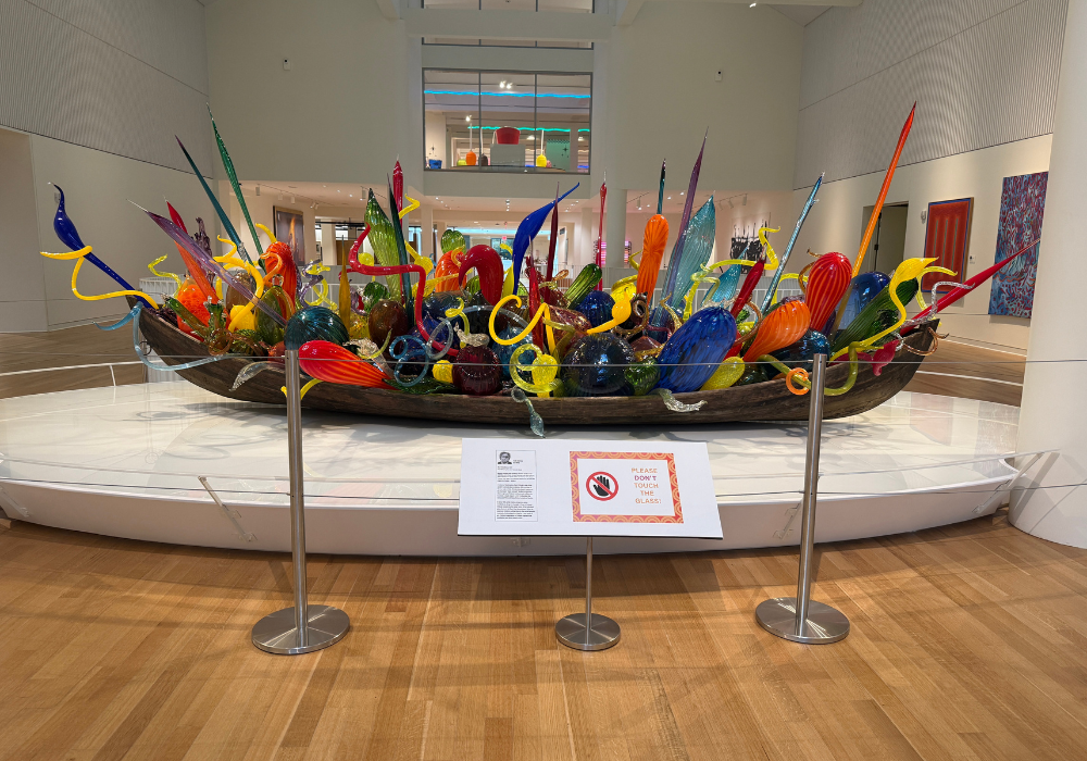 Large, colorful glass sculpture inside a wooden boat.