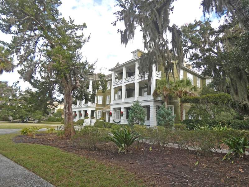 Three story green builsing with inset front section and white balconies.
