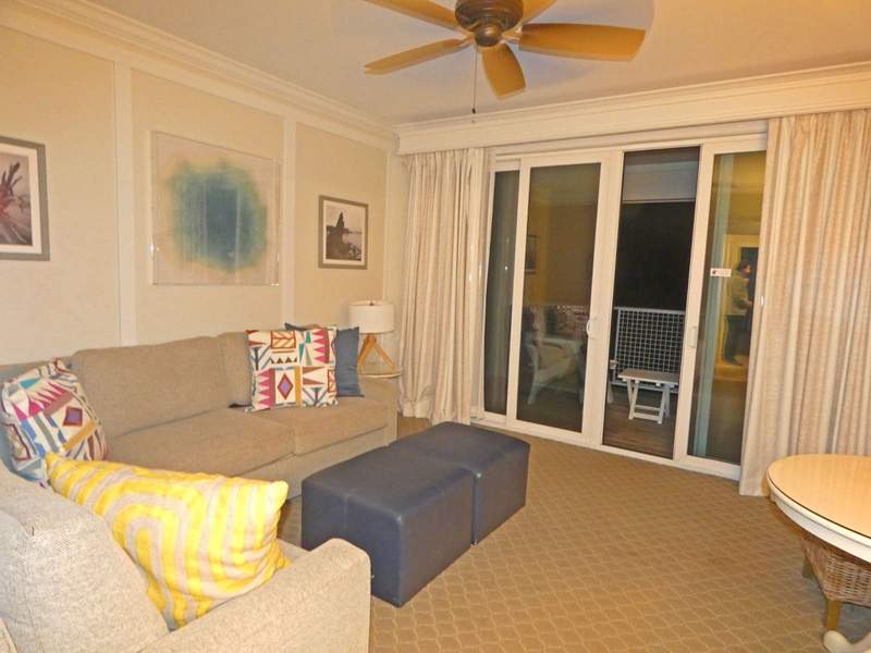 A living room with a beige sofa and easy chair and a balcony.