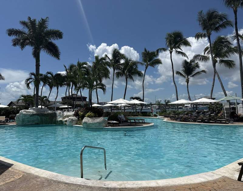 Pool at Warwick Paradise Island showing the cool water lounge chairs and umbrellas along with blue sky and puffy clouds.