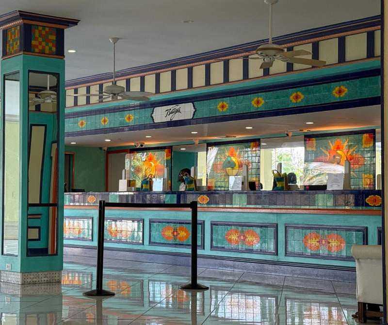 The image shows the very colorful and bright registration area of Breezes Bahamas. Aqua and orange are primary colors used along with a smooth tile floor.