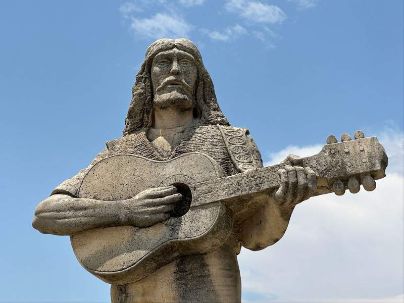 A Limestone Statue of a man playing a guitar on the Kansas Gunsmoke Trail.