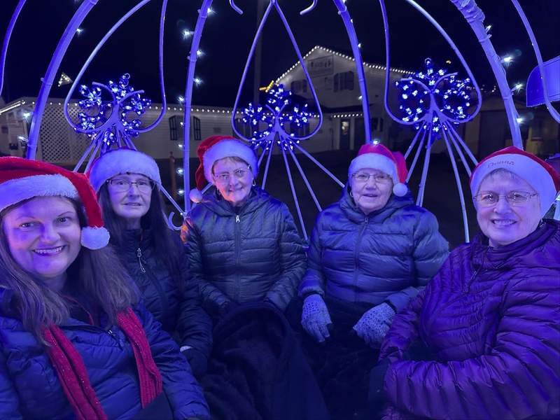 A group of ladies wearing Santa hats and winter coats.