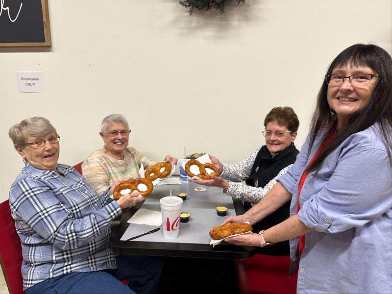 Four ladies holding soft pretzels in a restaurant booth.