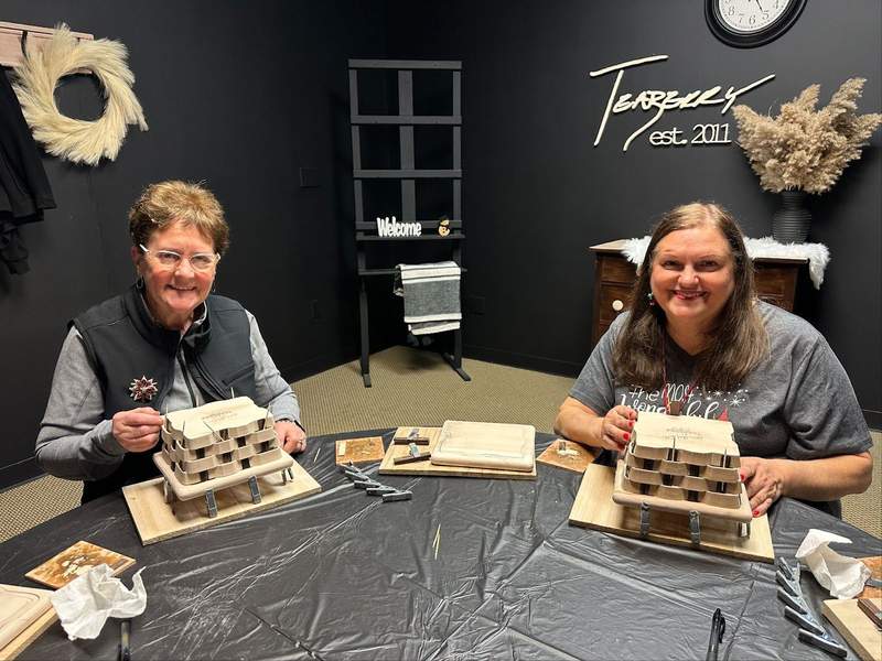 Two ladies with wooden baskets in front of them. 