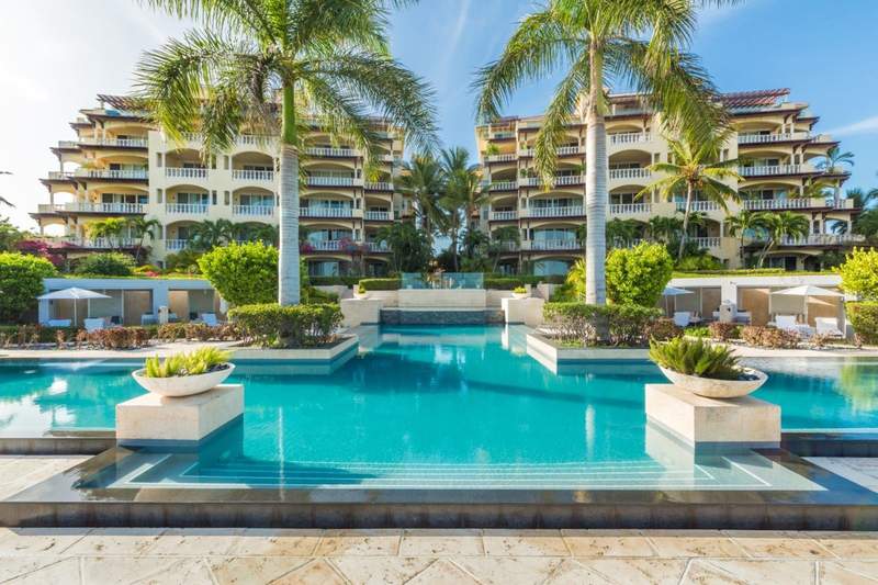 Turquoise pools green palm trees and buildings at Grace Bay Club Turks and Caicos