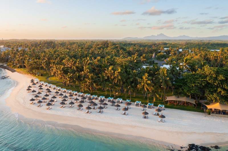 Huts on white sand beach with rainforest background at OneAndOnly Le Saint Geran Mauritius