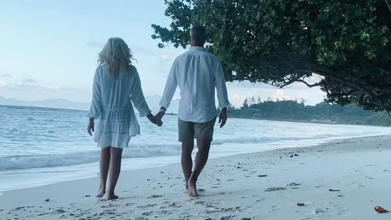 A couple walking on the beach in the Seychelles.
