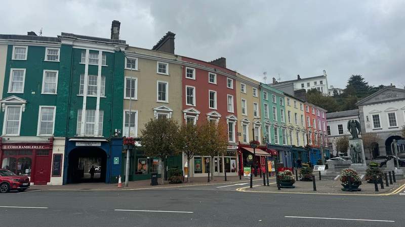 rainbow buildings next to an empty town square and a statue in Cobh. 