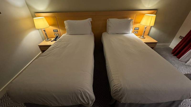 two twin beds in a room on top of a geometric carpet and two lanterns by a wooden headboard at Pembroke Hotel in Kilkenny.
