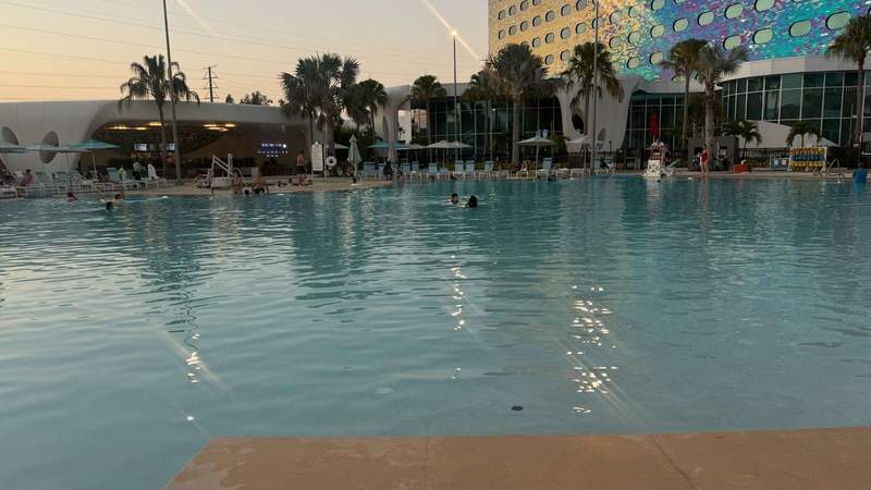 clear blue pool and palm trees against rainbow scales and windows of the Universal Terra Luna Resort Orlando. 