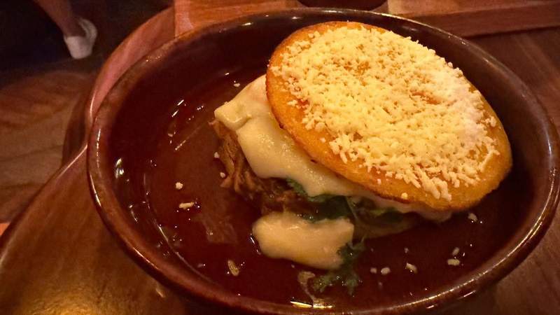 brown plate with brown sauce and a yellow area with sprinkled cheese on top and chicken from The Beak and Barrel. 