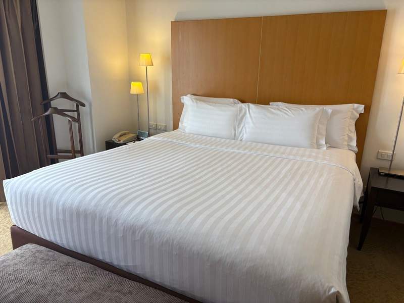 A cozy white king size bed with warm lights around it