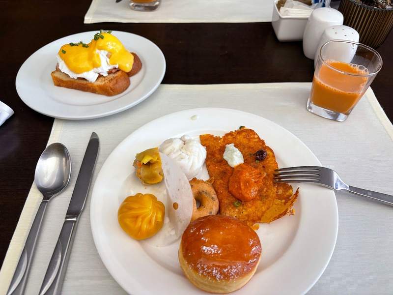 A plate of eggs Benedict, dumplings fried pancakes and donut