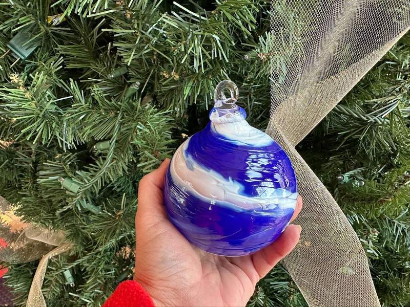 a hand holding a blue and white Christmas ornament.