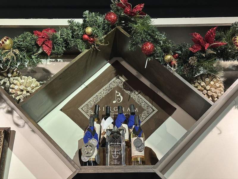 Several bottles of wine with ribbons and medals on them along with some Christmas decorations.