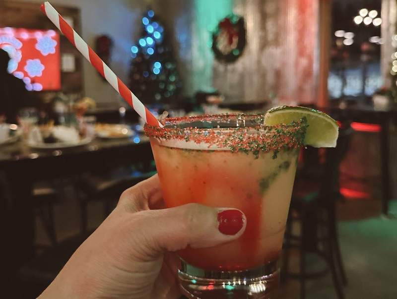 A festive drink with red and green sugar around the rim and a red and white straw.