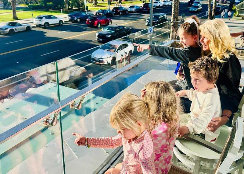 A grandmother sitting on a hotel balcony with grandchildren overlooking the beach in Santa Monica
