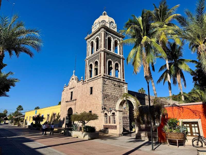 Historic mission with palm trees and cobalt blue sky