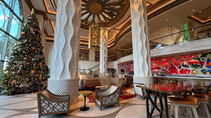 A lobby and bar with a Christmas tree and wooden chairs. 