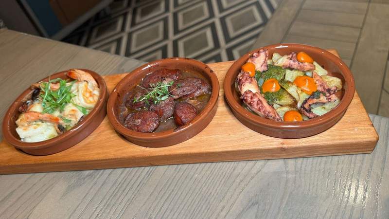 An appetizer plate with shrimp octopus and chorizo in three separate bowls. 