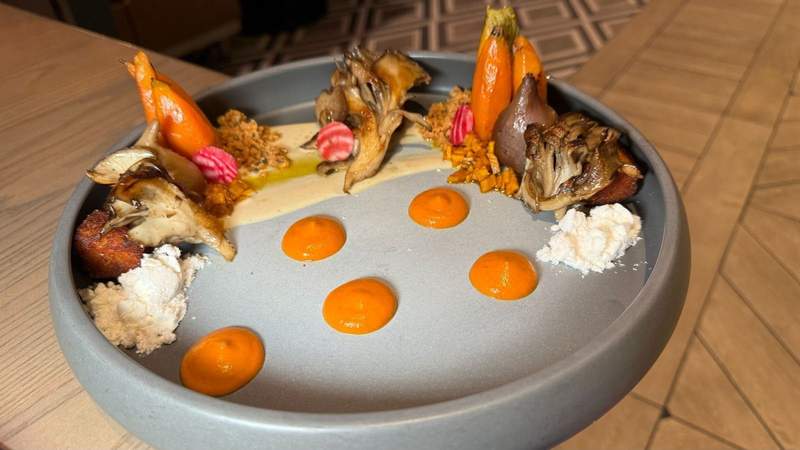 A plate with blue vegetables and carrots on a wooden table. 