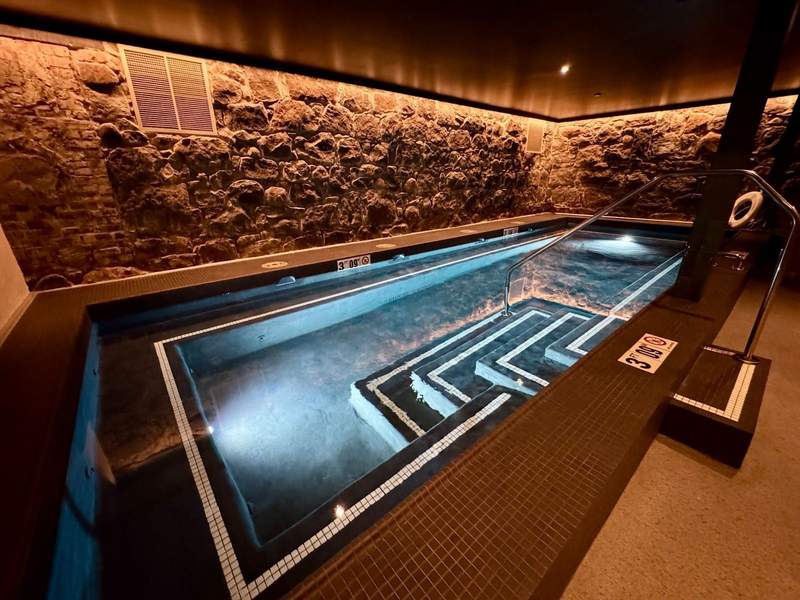 Large underground hot tub surrounded by original rock walls.
